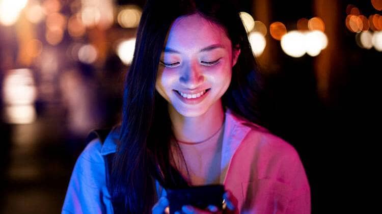 Mulher jovem usando TikTok no celular e sorrindo